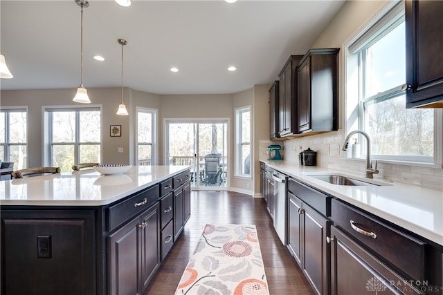 kitchen with sink, tasteful backsplash, dark hardwood / wood-style floors, decorative light fixtures, and a center island