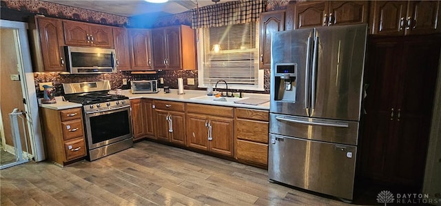 kitchen with wood-type flooring, sink, appliances with stainless steel finishes, and tasteful backsplash