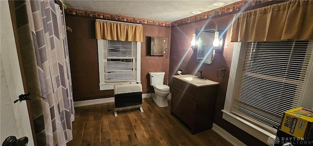 bathroom with hardwood / wood-style floors, vanity, toilet, and heating unit