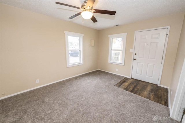 entryway featuring dark colored carpet, ceiling fan, and a textured ceiling