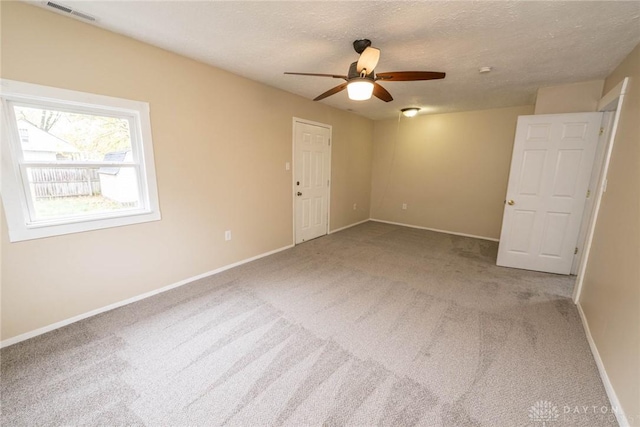 carpeted empty room featuring ceiling fan and a textured ceiling