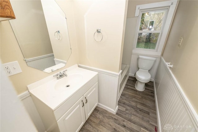 bathroom with vanity, wood-type flooring, a bathing tub, and toilet