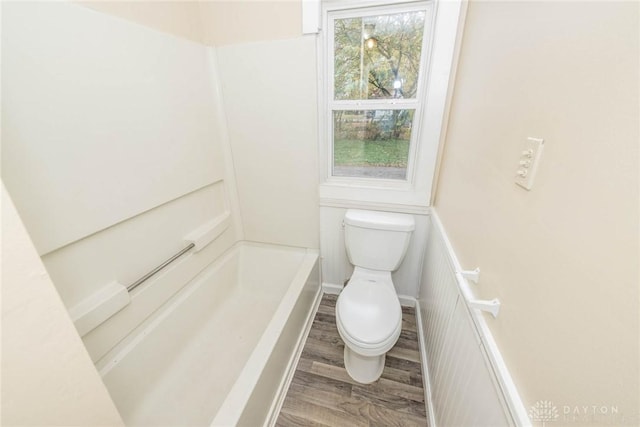 bathroom featuring wood-type flooring, a bathtub, and toilet