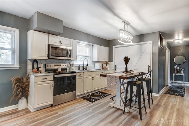 kitchen featuring pendant lighting, appliances with stainless steel finishes, sink, and white cabinets