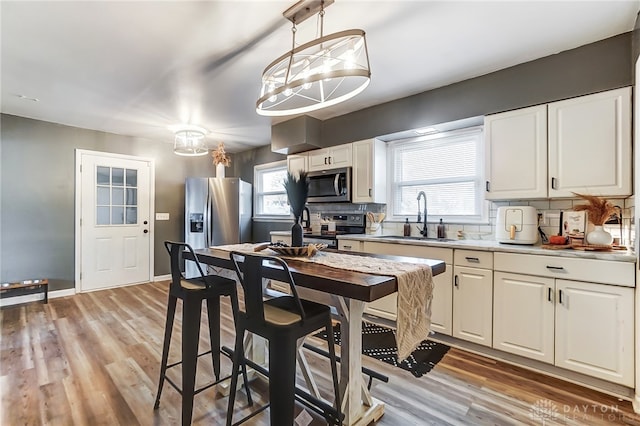 kitchen with stainless steel appliances, white cabinetry, decorative light fixtures, decorative backsplash, and sink