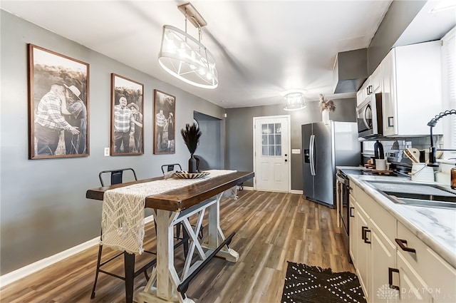 kitchen with stainless steel appliances, an inviting chandelier, hanging light fixtures, sink, and dark hardwood / wood-style floors