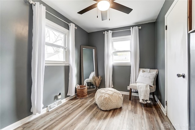 living area featuring ceiling fan, wood-type flooring, and a healthy amount of sunlight