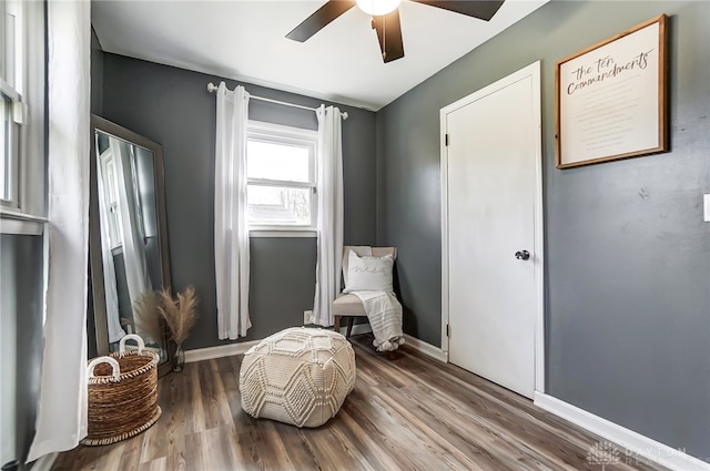 sitting room with ceiling fan and wood-type flooring