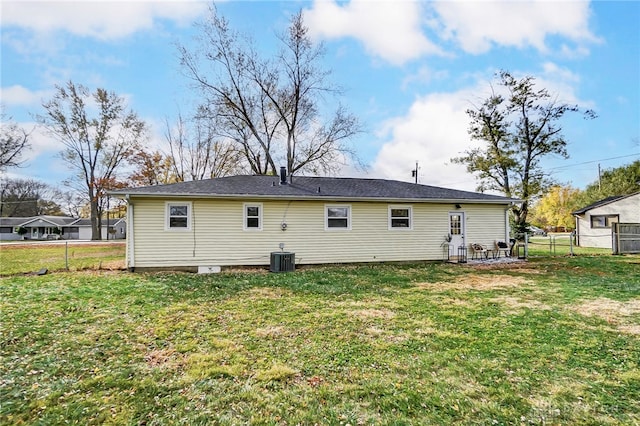 rear view of property with central AC and a lawn