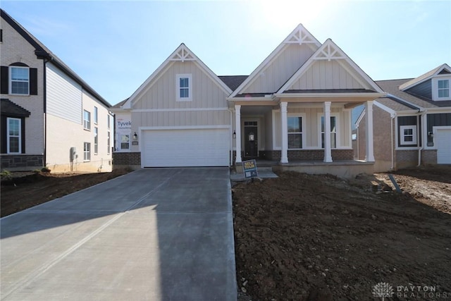 craftsman inspired home featuring brick siding, covered porch, board and batten siding, and driveway