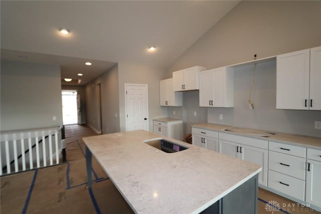 kitchen featuring a center island, a kitchen bar, white cabinetry, and high vaulted ceiling