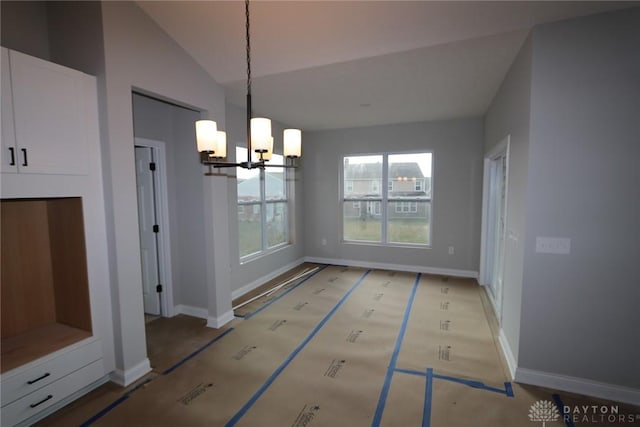 unfurnished dining area featuring a chandelier and vaulted ceiling