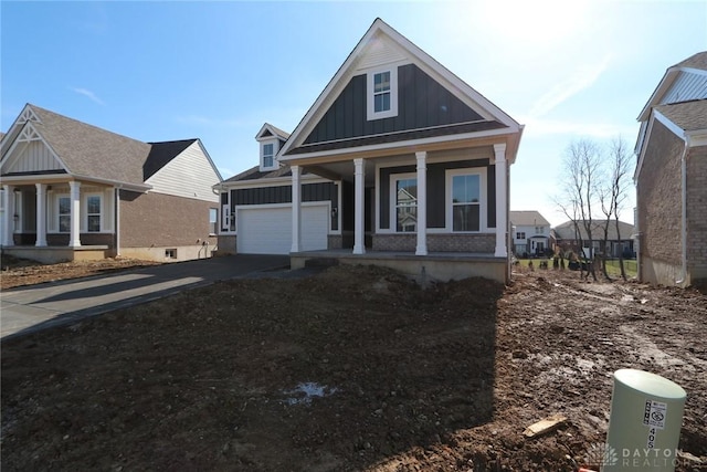 view of front facade with brick siding, a porch, concrete driveway, an attached garage, and board and batten siding