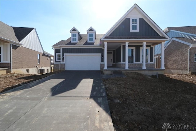 view of front of house featuring a garage, concrete driveway, covered porch, central air condition unit, and board and batten siding