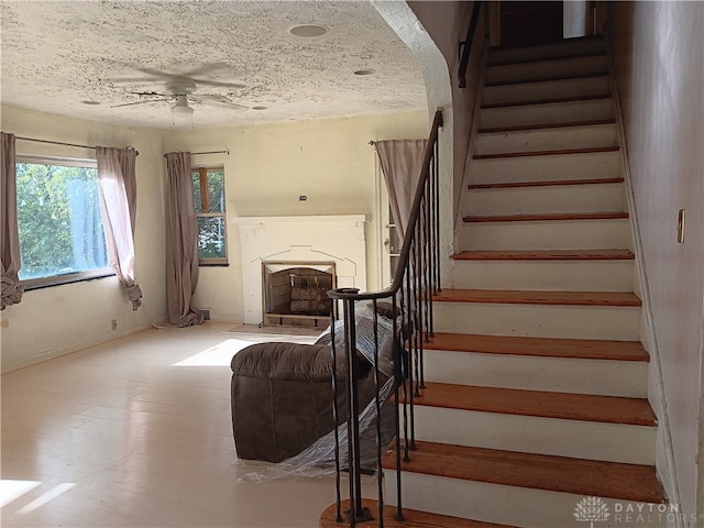 stairs featuring ceiling fan and a textured ceiling