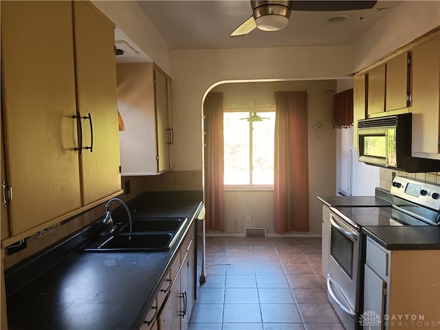 kitchen featuring sink, dishwashing machine, electric range oven, ceiling fan, and light tile patterned floors