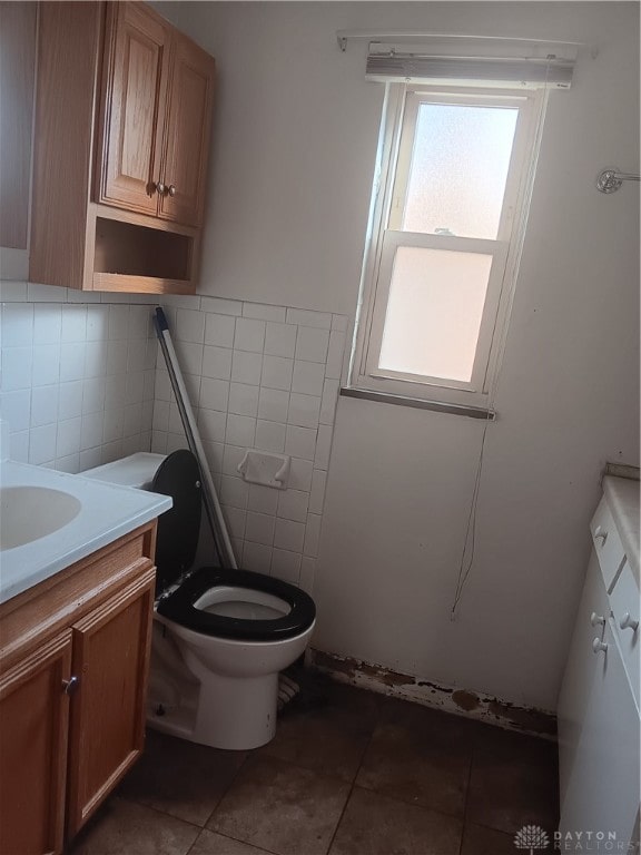 bathroom featuring toilet, vanity, tile walls, and tile patterned floors