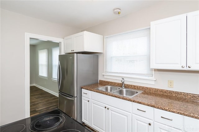 kitchen featuring sink, white cabinets, stove, and stainless steel refrigerator