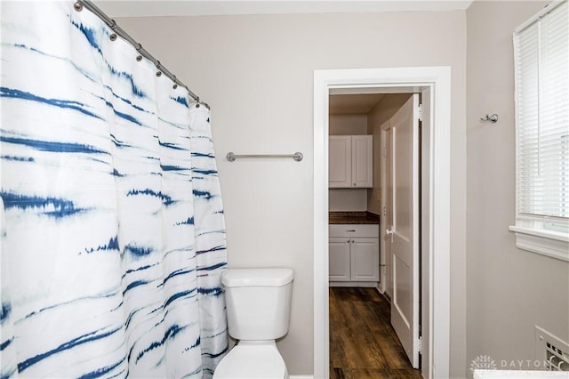 bathroom with wood-type flooring, toilet, and a shower with shower curtain