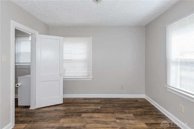 unfurnished room featuring a textured ceiling and dark hardwood / wood-style flooring