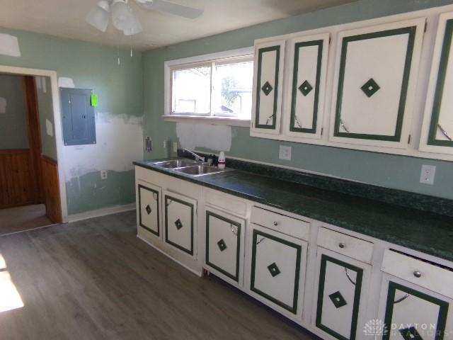 kitchen featuring electric panel, white cabinetry, sink, and dark hardwood / wood-style floors