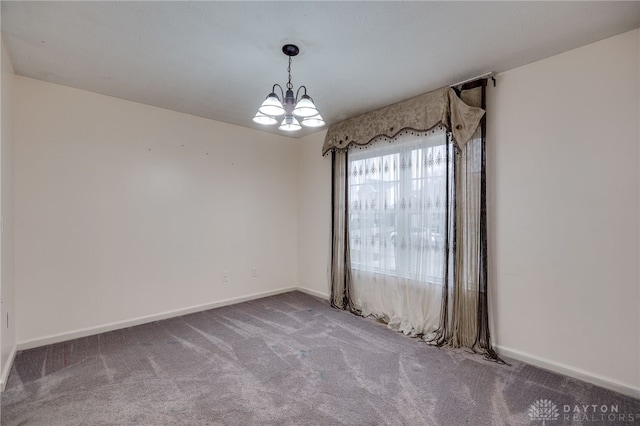 spare room with baseboards, carpet, and an inviting chandelier