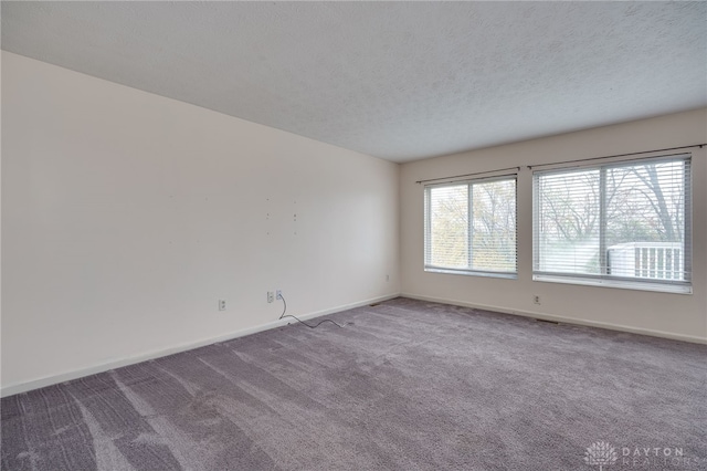 unfurnished room featuring carpet, a textured ceiling, and baseboards