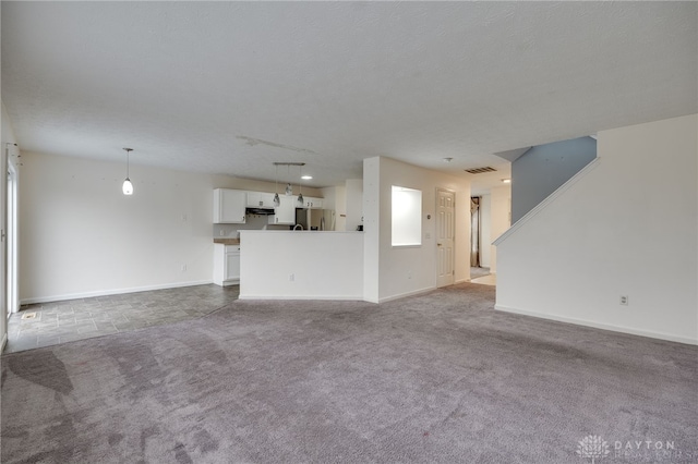 unfurnished living room featuring baseboards, visible vents, and carpet flooring