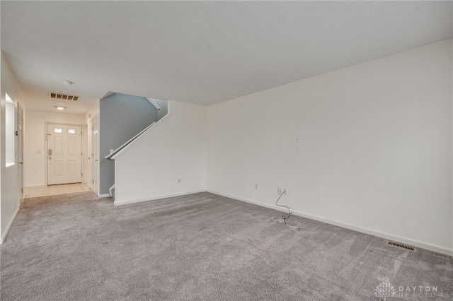 unfurnished living room with carpet floors, baseboards, stairs, and visible vents