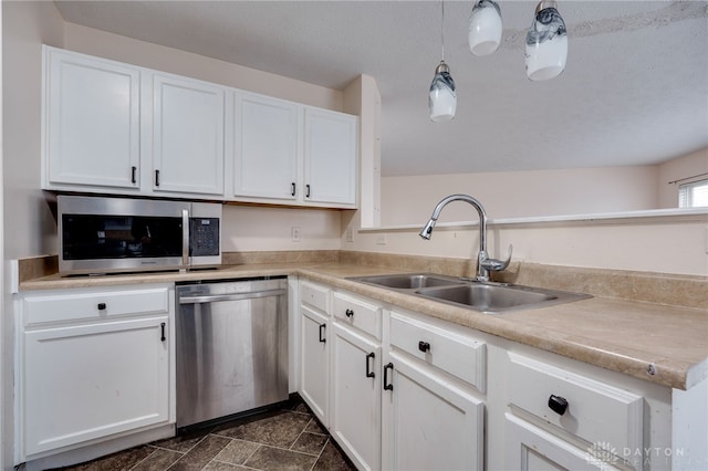 kitchen featuring appliances with stainless steel finishes, light countertops, white cabinets, and a sink