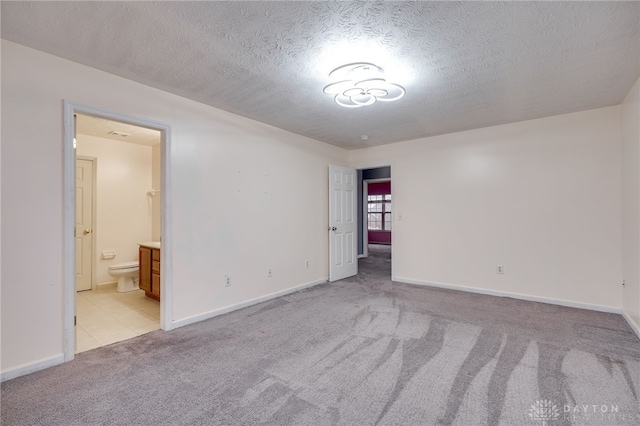 unfurnished room featuring light carpet, a textured ceiling, and baseboards