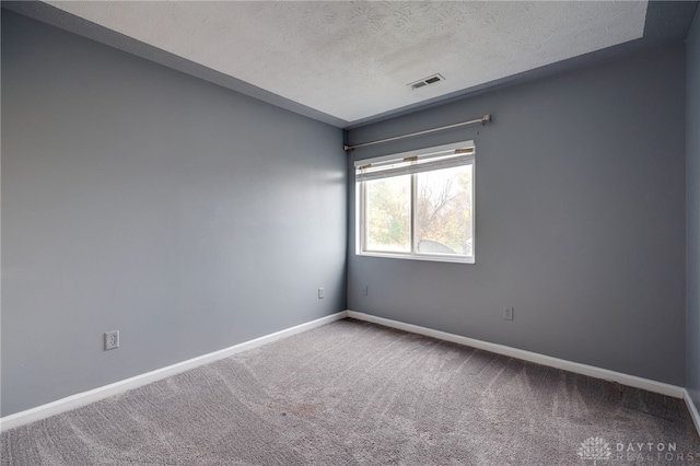 carpeted spare room featuring baseboards, visible vents, and a textured ceiling