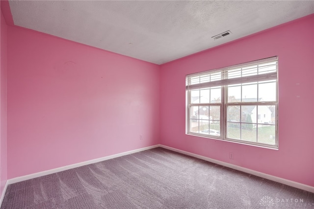 carpeted empty room featuring a textured ceiling, visible vents, and baseboards