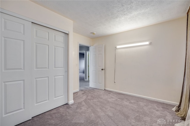 unfurnished bedroom with a textured ceiling, a closet, carpet, and baseboards