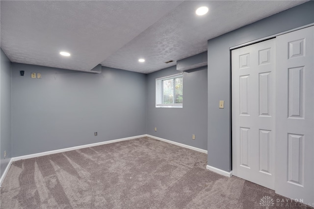 below grade area featuring carpet, baseboards, a textured ceiling, and recessed lighting