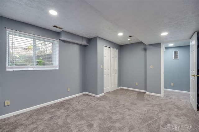 basement featuring carpet floors, baseboards, a textured ceiling, and recessed lighting