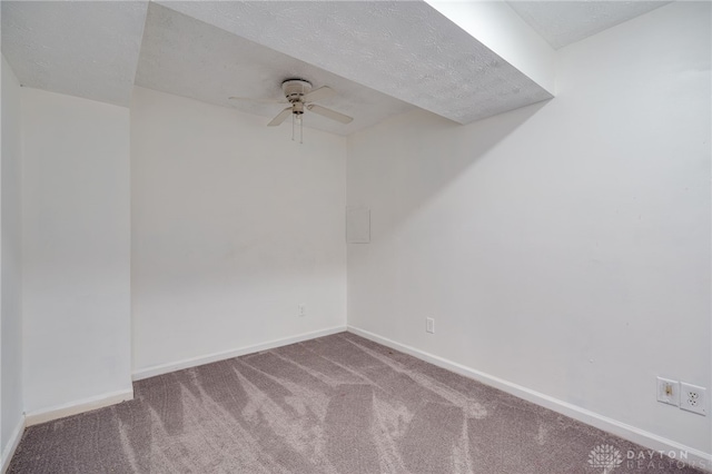 carpeted spare room with a textured ceiling, baseboards, and a ceiling fan