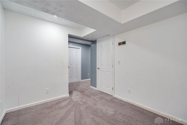 carpeted spare room featuring visible vents, a textured ceiling, and baseboards