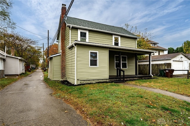 view of front facade featuring a front lawn, a garage, and an outbuilding