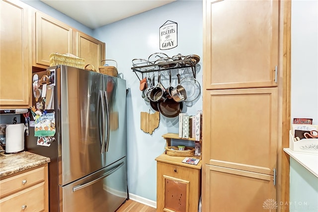 kitchen featuring light brown cabinets, stainless steel refrigerator, and light hardwood / wood-style flooring