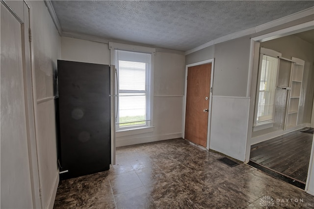 foyer entrance featuring a textured ceiling and crown molding