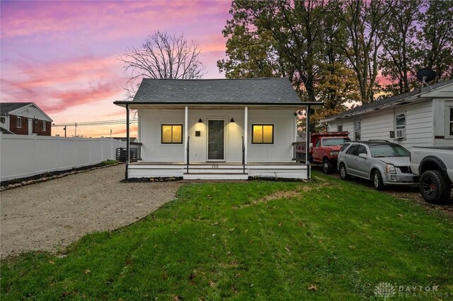 view of front of house featuring cooling unit, a yard, and a porch