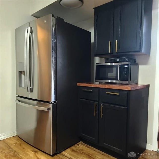 kitchen featuring stainless steel appliances, light wood-style floors, wooden counters, and baseboards