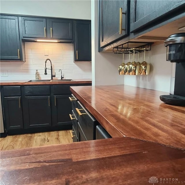 bar with sink, light hardwood / wood-style floors, butcher block countertops, and decorative backsplash