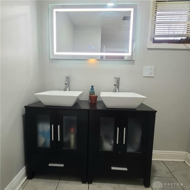 bathroom featuring double vanity, baseboards, a sink, and tile patterned floors