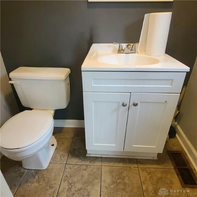 half bathroom with visible vents, toilet, vanity, tile patterned flooring, and baseboards