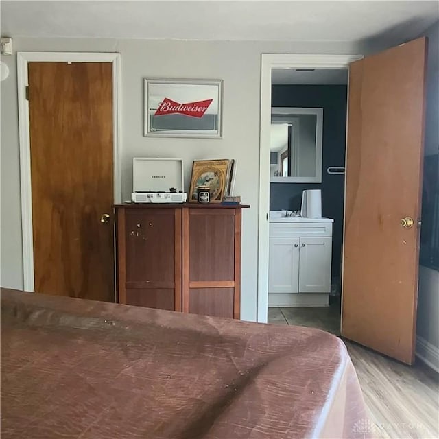 bedroom featuring connected bathroom and wood finished floors