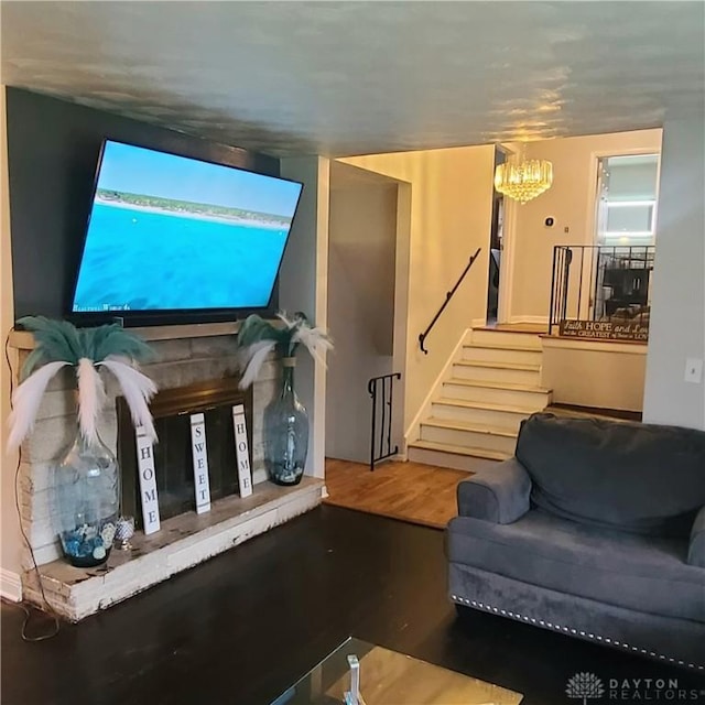 living room featuring an inviting chandelier, stairway, and wood finished floors