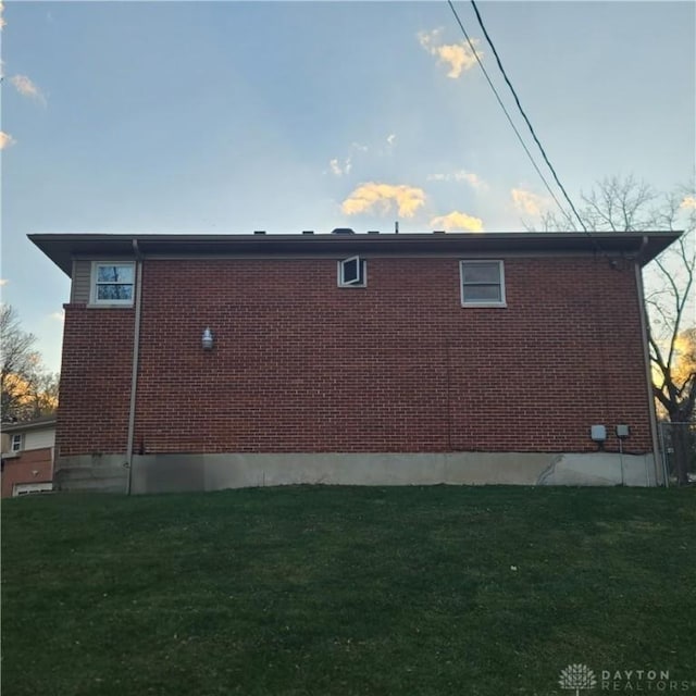 view of side of home featuring brick siding and a yard