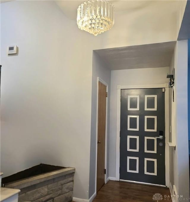 foyer entrance with baseboards, wood finished floors, and an inviting chandelier